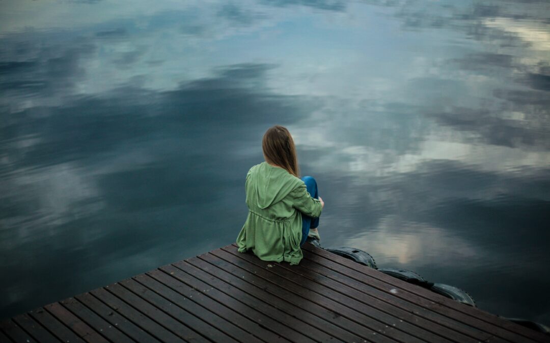 jeune fille assise devant un lac